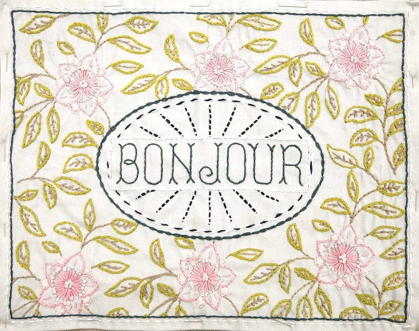 Embroidery design with 'Bonjour' text surrounded by floral and leaf patterns on a white background.