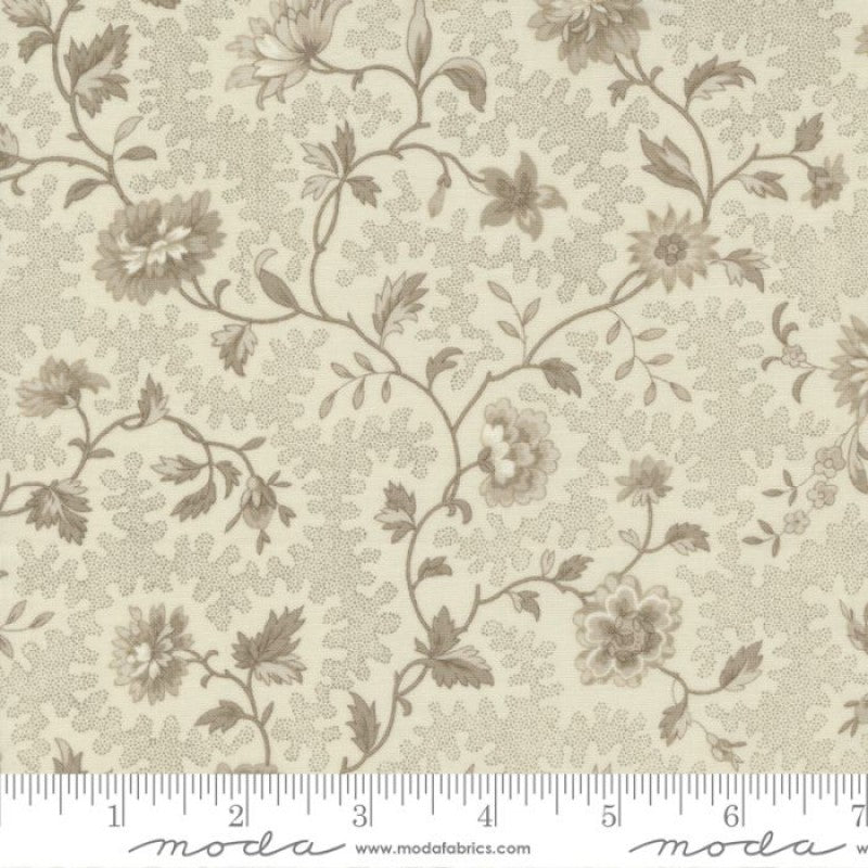 A yardstick measuring the width of a piece of Quilting fabric, which is adorned with a floral design in shades of beige and brown.
