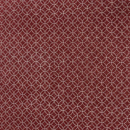 A close-up image of a red fabric with a small white geometric design design.