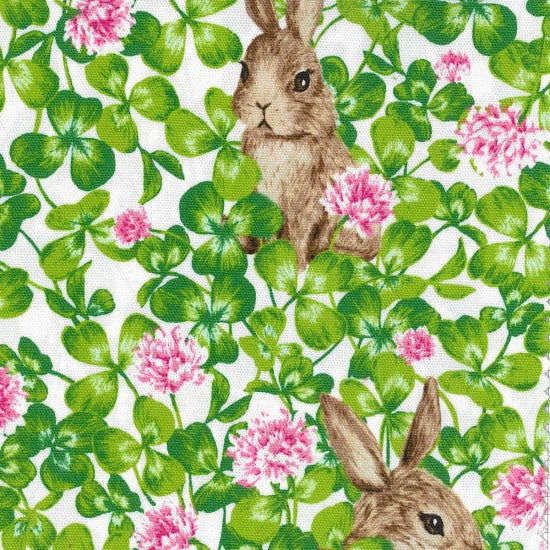 Quilting Fabric with a design of rabbits and green foliage on an off-white background.