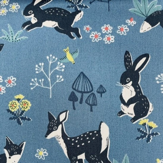 A Quilt fabric featuring a variety of animals including bunnies, foxes, and fawns in a forest scene on a blue background, with floral and mushroom motifs.