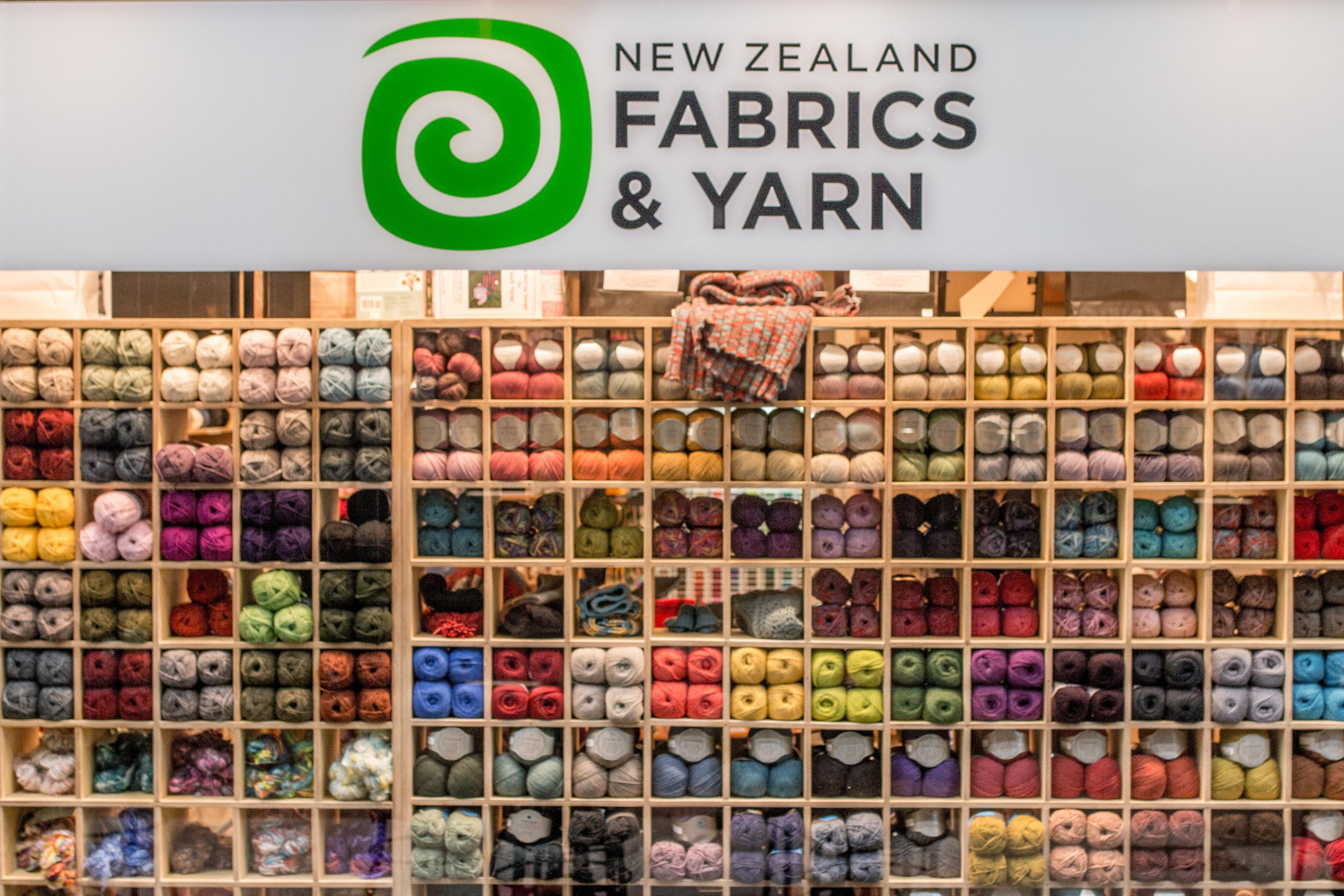 Display of colorful yarn balls with 'New Zealand Fabrics & Yarn' branding.