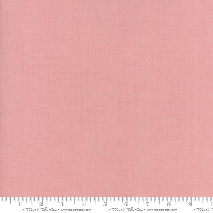 A pale rose colored blender quilting fabric with a measuring scale at the bottom, marked with 'Moda' brand name.