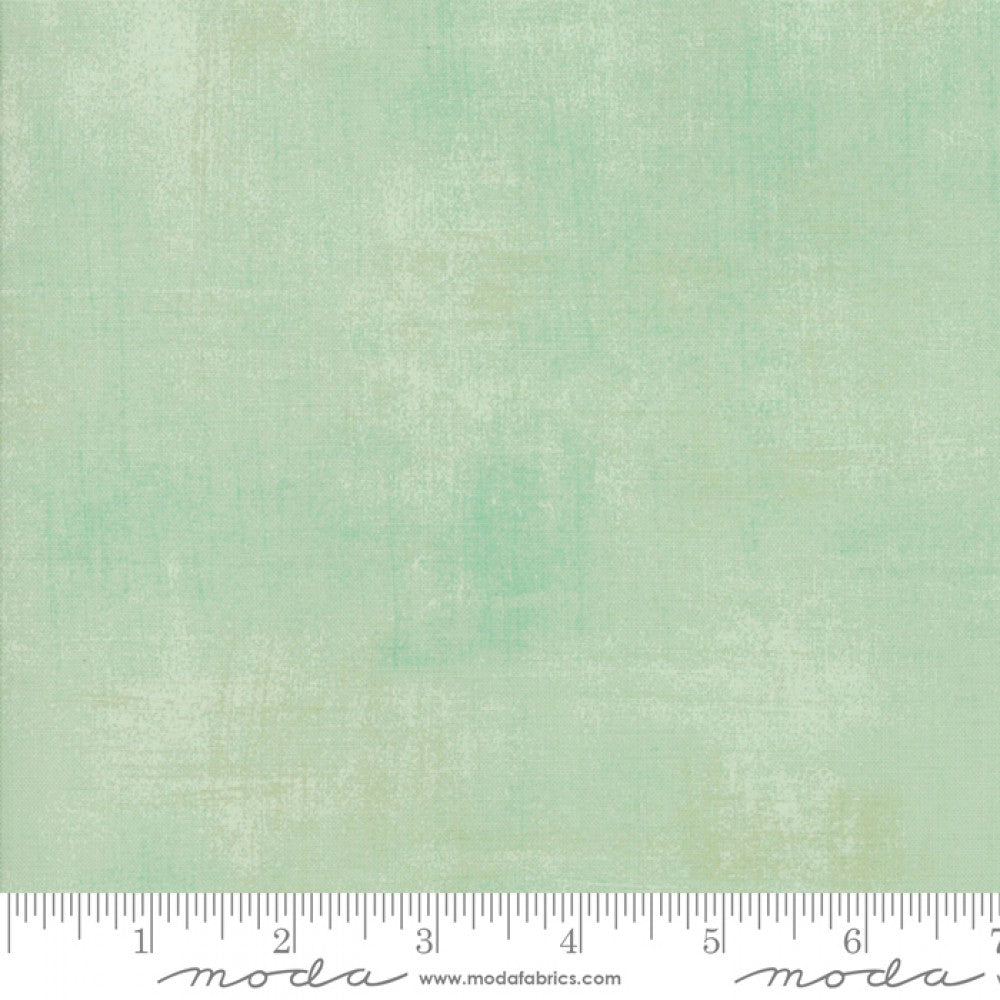 A swatch of textured quilt fabric with a pale green design.