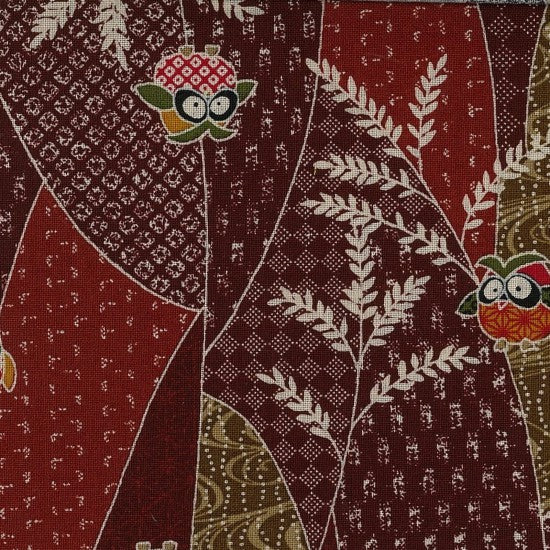 A piece of traditional Japanese fabric featuring a design with owls and leaves on a dark red background.