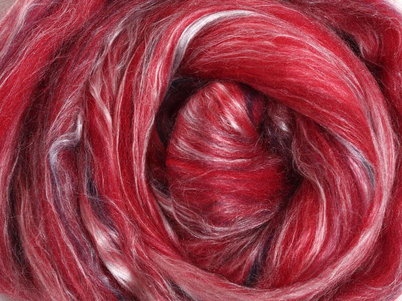 Close up picture of a sample of New Zealand Merino and Silk unspun fibre dyed in multi-colour  berry reds