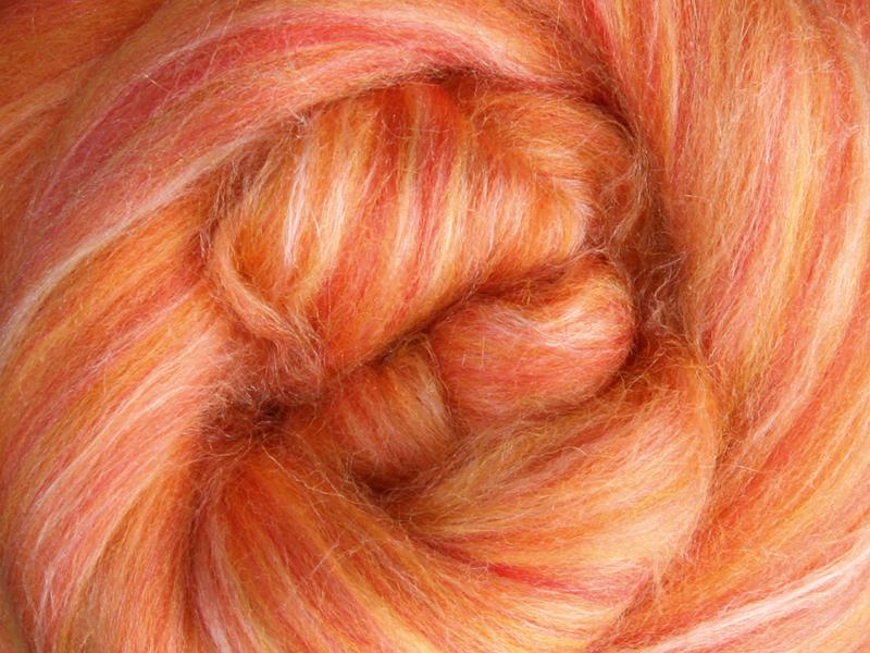Close up picture of a sample of New Zealand Merino and Silk unspun fibre dyed in multi-colour  oranges