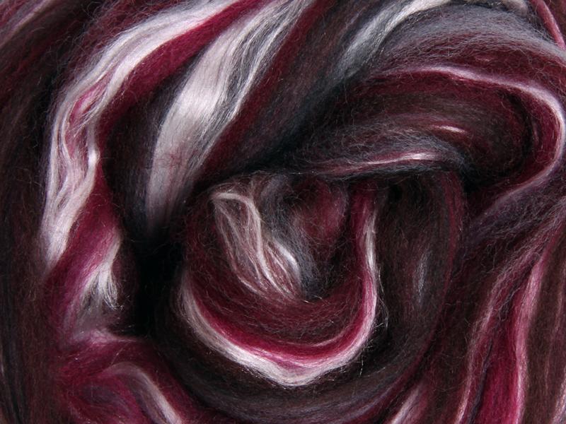 Close up picture of a sample of New Zealand Merino and Silk unspun fibre dyed in multi-colour storm purples and reds