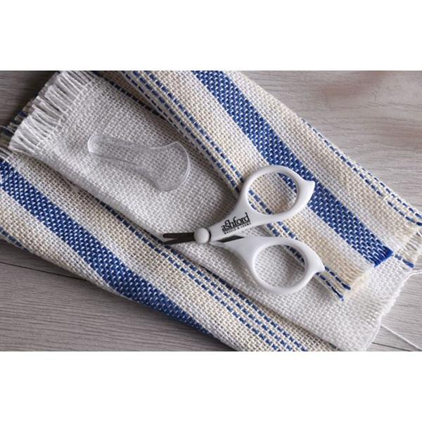 White scissors on a blue and white striped fabric background