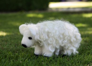 White needle felted sheep sample on grass 
