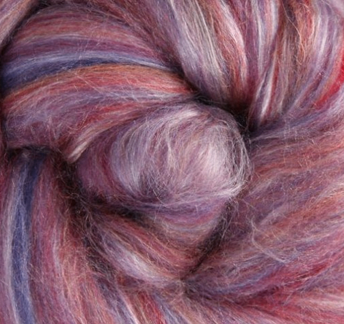 Close-up of a hank of multicolored merino and silk fibre with shades of pink, purple, and red.