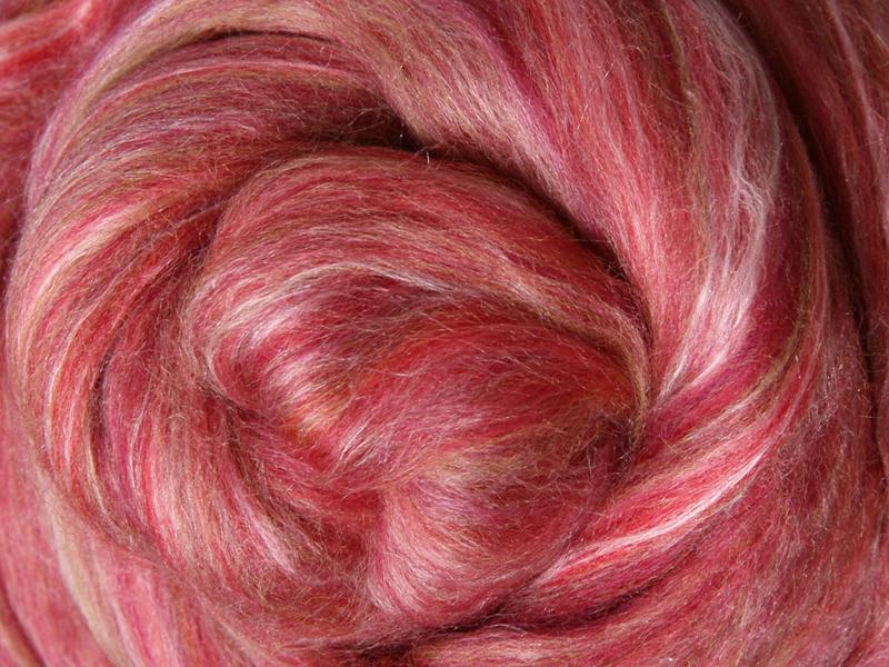 Close up picture of a sample of New Zealand Merino and Silk unspun fibre dyed in multi-colour pomegranite reds