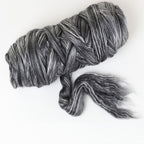 Gray and black bundle of merino and silk fibre on a white background
