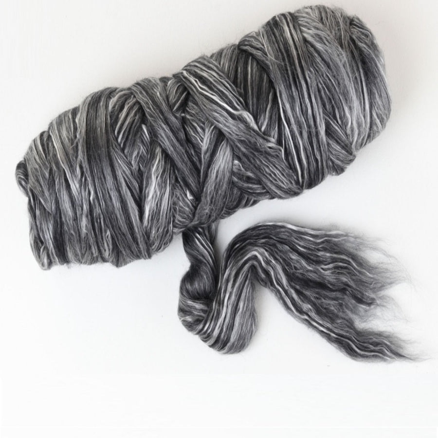 Gray and black bundle of merino and silk fibre on a white background
