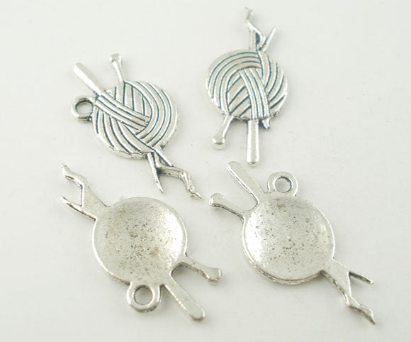 Antique silver charms in the shape of yarn balls, intended for use in crafting and jewelry making.