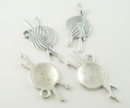 Antique silver charms in the shape of yarn balls, intended for use in crafting and jewelry making.