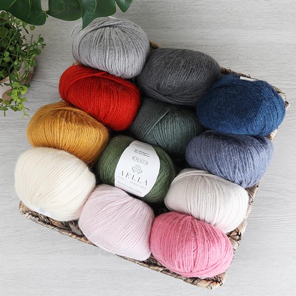 Assorted colors of yarn on a wooden board with a plant in the corner.