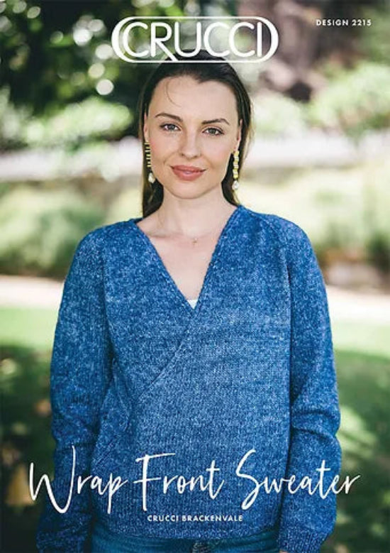 A woman wearing a blue wrap front cardigan with a V-neck, knitting pattern leaflet in front.