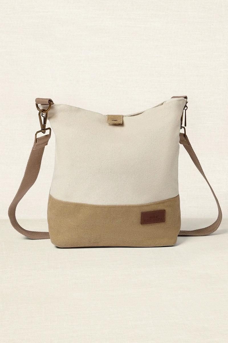 Beige and white canvas bag with brown leather accents on a beige background