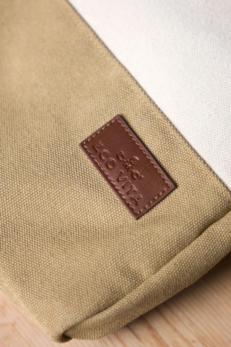 Close-up of a beige fabric with a brown leather label on a light wooden surface.