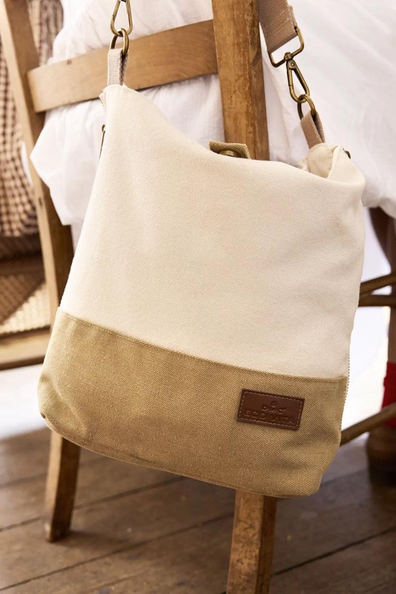 Beige and brown canvas bag with a leather patch on a wooden chair.