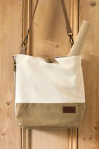Canvas tote bag with leather accents against a wooden door
