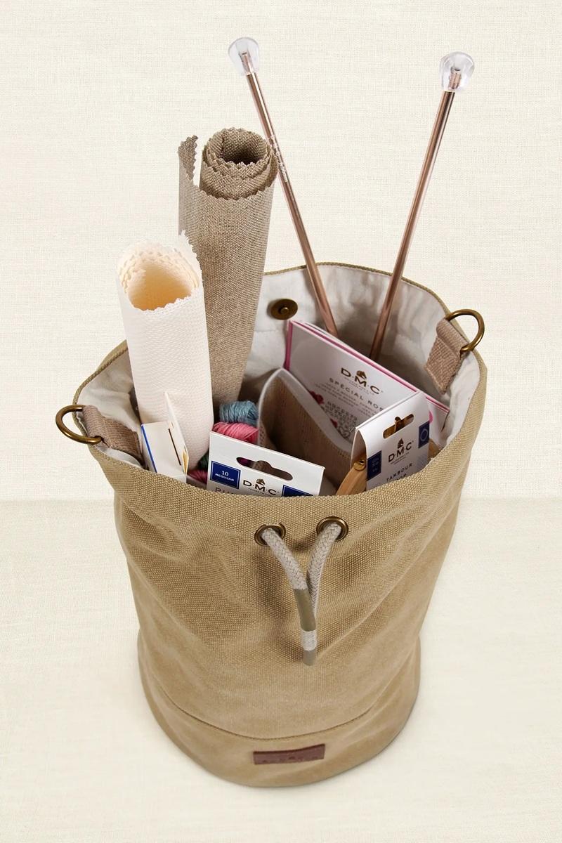 Beige storage bag with knitting supplies on a beige background