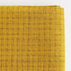 Close-up of a mustard yellow Sashiko fabric with a per=printed grid pattern on a white background