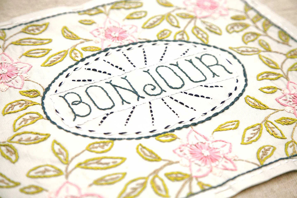 Embroidered fabric with 'Bonjour' text and floral patterns
