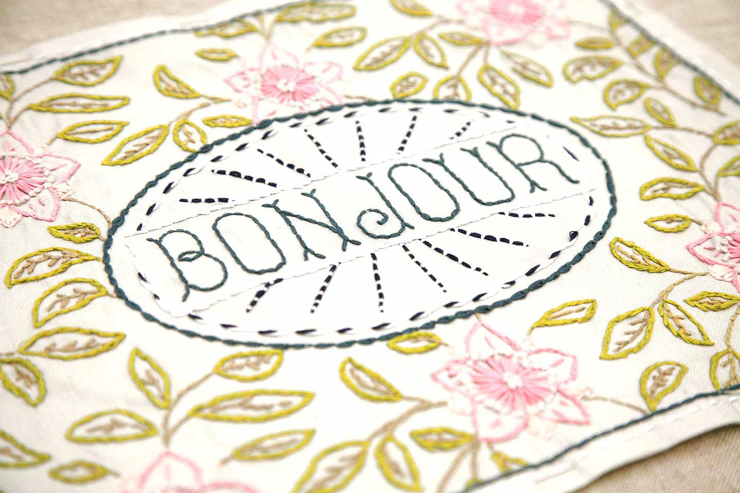 Embroidered fabric with 'Bonjour' text and floral patterns