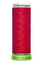 Red spool of Güterman thread on a white background
