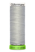 Spool of pale grey Gutermann thread on a white background