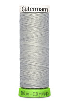 Spool of pale grey Gutermann thread on a white background