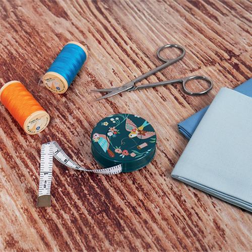 Sewing tools including scissors, thread, and fabric on a wooden surface