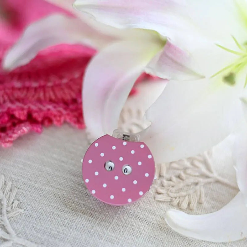 Pink polka dot row counter for knitting or crochet on a table with ribbons
