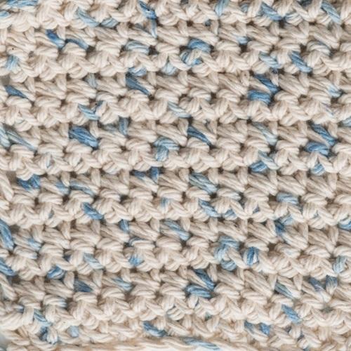 Close-up of a crocheted fabric with beige and blue pattern