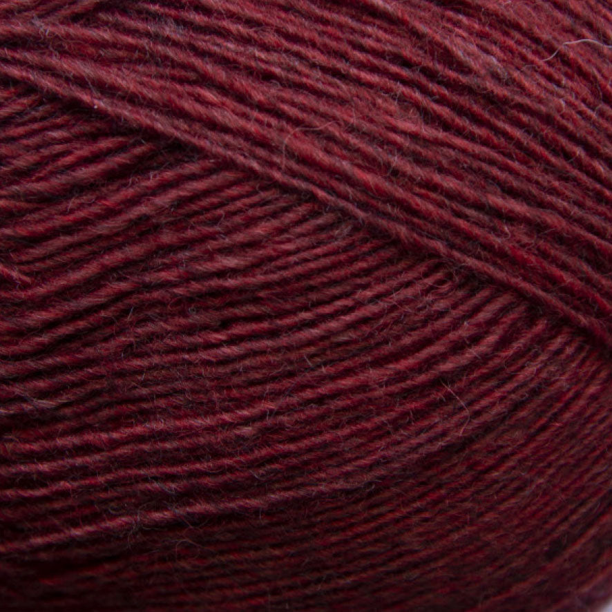 Close-up of a ball of dark cherry red yarn with a textured pattern