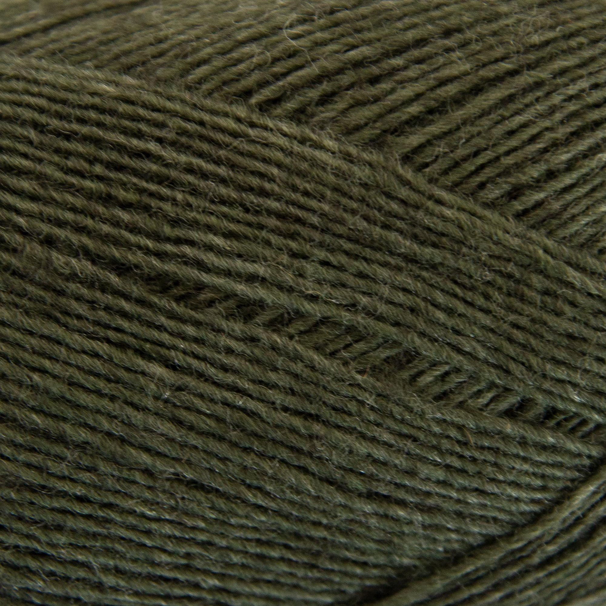 Close-up of a ball of dark green yarn with a textured pattern