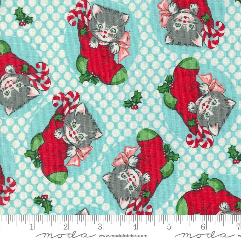 A fabric from the Kitty Christmas collection by Urban Chiks, featuring a design of gray cats in red Christmas stockings with decorative elements and a polka dot background.