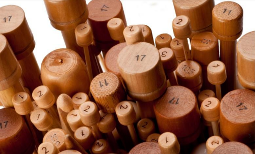 A collection of ChiaoGoo wooden straight knitting needles in various sizes, with natural color wood finish.