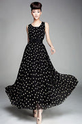 A model wearing a black and white dotted chiffon dress with a sweetheart neckline and a belted waist.