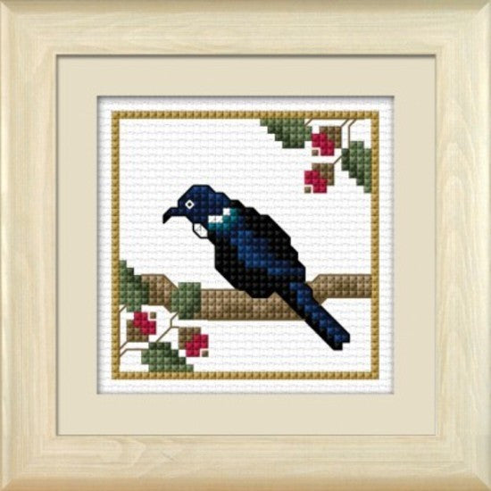A completed cross-stitch kit depicting a New Zealand Tui bird, framed in a wooden frame.