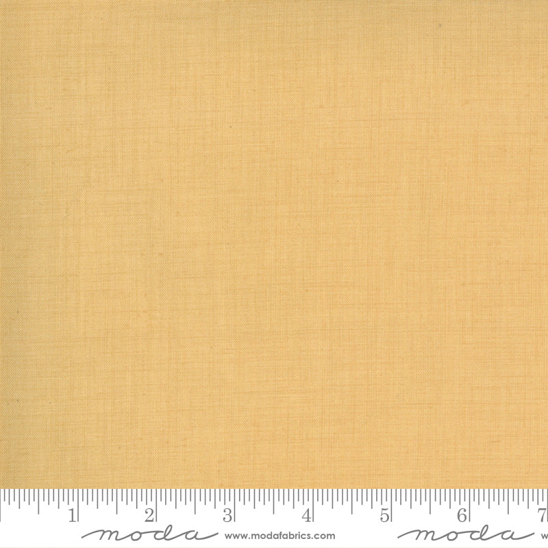 A yardstick measuring fabric width, with the mustard-colored fabric labeled with 'moda' brand.