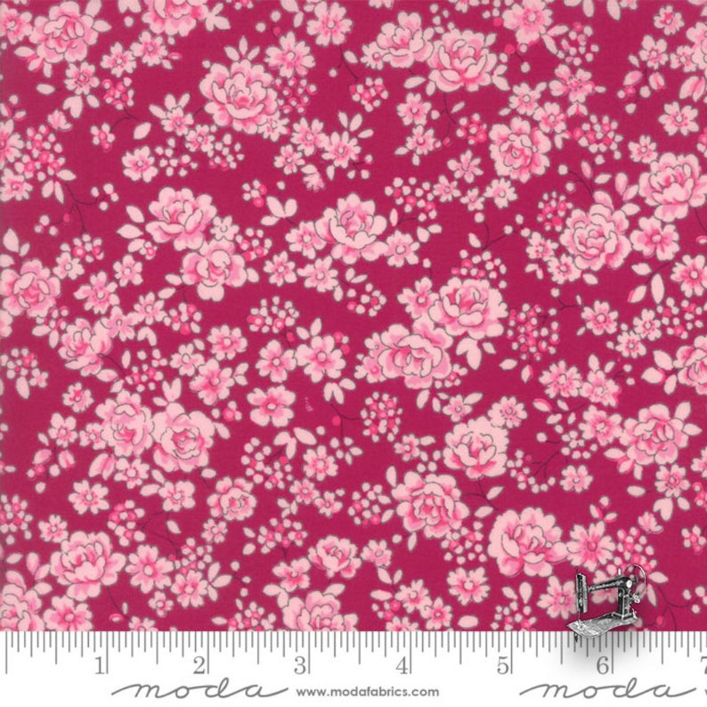 A yardstick measuring fabric with a floral Quilt Fabric consisting of pink roses on a red background.