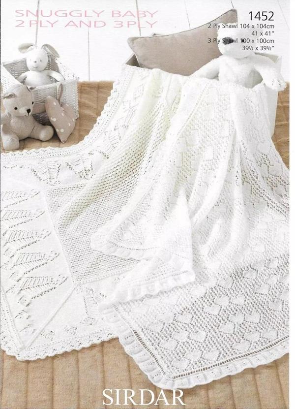 Knitted baby blanket with lace edge on a wooden surface, featuring Sirdar branding.