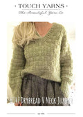 Person wearing a green knitted sweater with 'Touch Yarns' branding on a white background