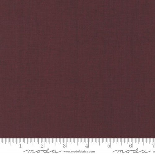 A solid red colored blender fabric from the French General collection by Moda, with a ruler at the bottom showing the width in inches.