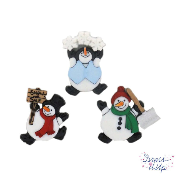 Three decorative penguin ornaments on a white background, with one holding a sign and another with a hat and scarf.
